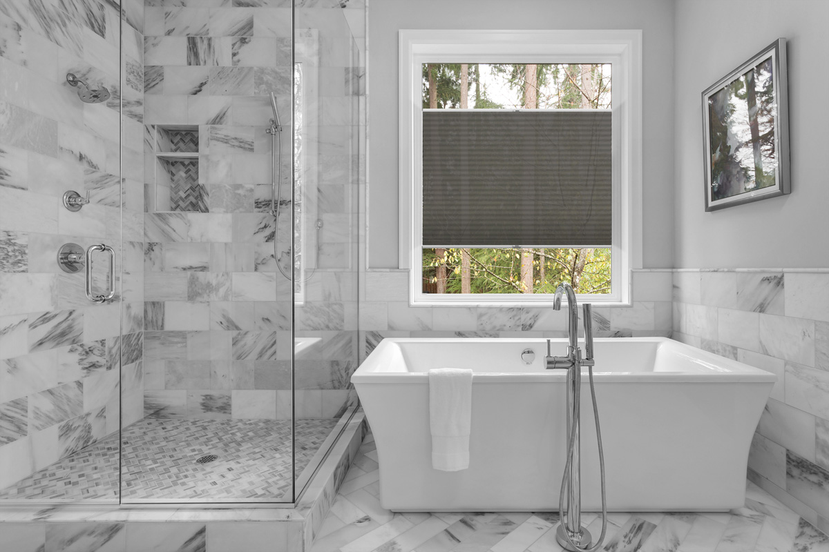 Bathroom with bathtub and shower in new luxury home with all gla